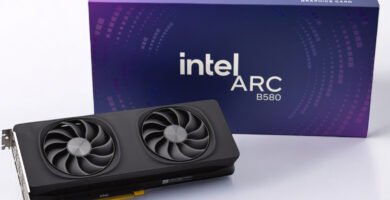 Bild der Grafikkarte neben ihrer blauen Verpackung auf weißem Hintergrund.